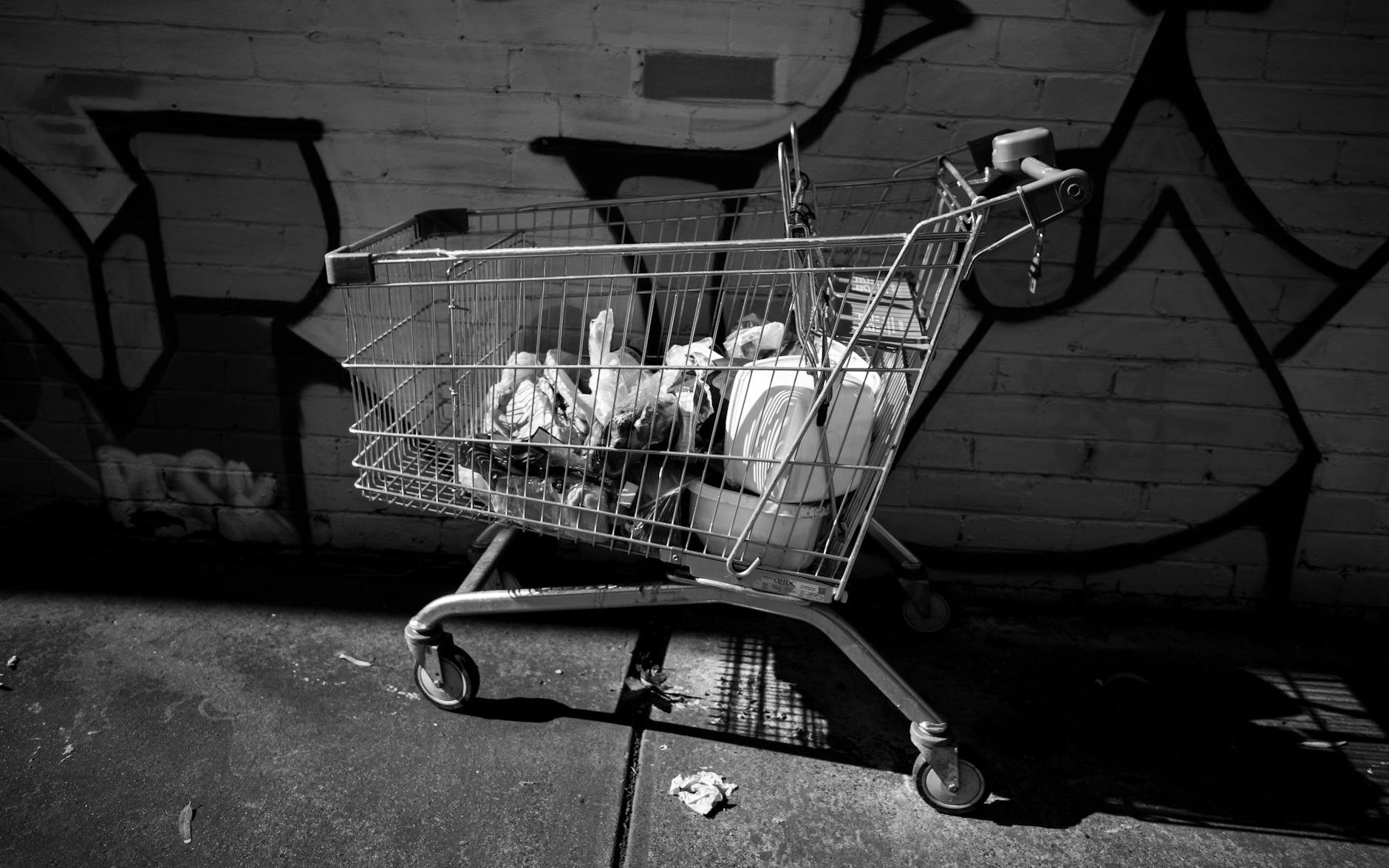 grayscale photo of a shopping cart with garbage